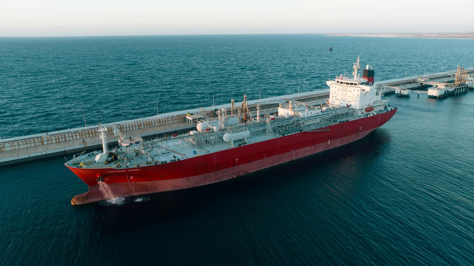 Aerial view of the LPG tanker Oceanic Moon alongside a loading jetty at sunset, calm sea.
